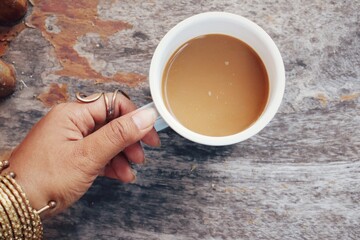 Hot coffee cup and hand on brown wood table background
