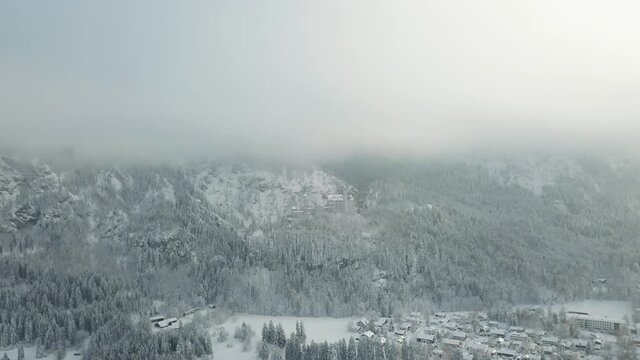 Aerial drone view of castle Neuschwanstein and schwangau in fog during winter in snow and ice in the Alps partly sunny, Germany