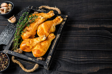 Smoked chicken leg drumsticks with herbs and spices. Black wooden background. Top view. Copy space