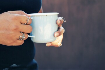 Woman drinking hot coffee beverage on cup and hand