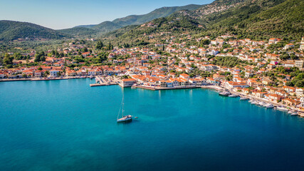 Aerial view of the capital town and the port of Vathy in Ithaca with a sailing boat moored in the middle