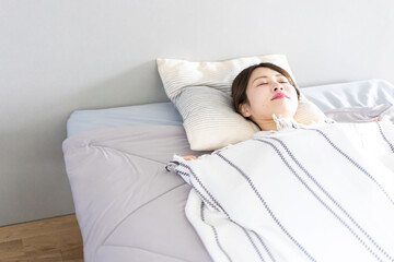 ベッドで熟睡する若い女性