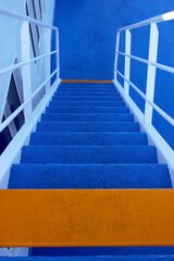 Cruise ship stairs with blue and orange steps going down. Selective focus