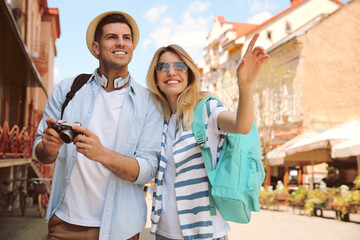 Happy couple of tourists with camera on city street