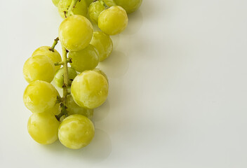 close-up of bunch of green grapes with drops on white background