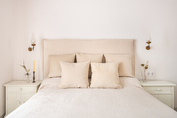 Bright bedroom interior, cozy bed with beige linen, dry flowers on a bedside table. Retro and vintage style.