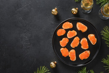 Russian appetizer canape with red caviar on ciabatta on black background for Christmas, New Year holidays party. Festive food. Close up.