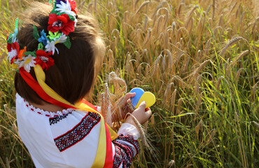 Ukrainian heart carried by a girl. A yellow and blue heart and spikelets of wheat in the hands of a...