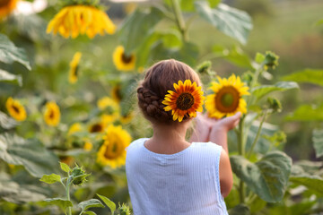 Beauty joyful girl with sunflower enjoying nature and laughing at summer sunflower field. Sun glare, sun rays, shining sun. High quality photo.