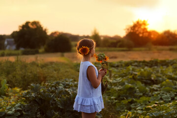 Obraz premium Beauty joyful girl with sunflower enjoying nature and laughing at summer sunflower field. Sun glare, sun rays, shining sun. High quality photo.