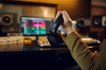 Engineer hand holds headphones, recording studio