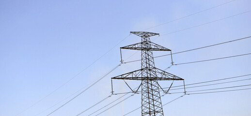 Electricity pylon overhead power line transmission tower with smoke from TPP (thermal plant) on a blue sky. Electrical Network Of High Voltage Transportation
