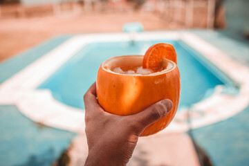 Vaso de melon con bebida tropical con fondo de pileta