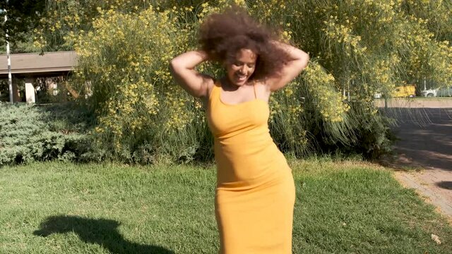 young curvy afro woman with curly hair dancing for viral video