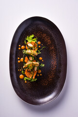 dish with salmon tartare, croutons, sauted courgettes and caper flowers. white background, top view