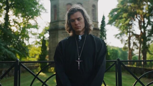Priest standing by the church. Dolly zoom.