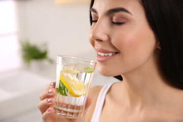 Young woman with glass of fresh lemonade at home, closeup