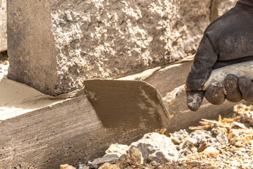 A person laying bricks and applying mortar to build a stonewall