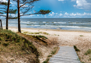 Wooden resting spot and footpath leading to sandy beach of the Baltic Sea