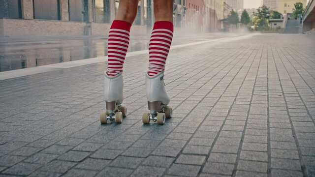 Close up shot of unrecognizable woman legs wearing striped knee-highs and classic roller skates rollerblading