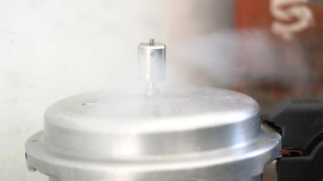Slow motion shot of steam releasing from a pressure cooker in a kitchen.