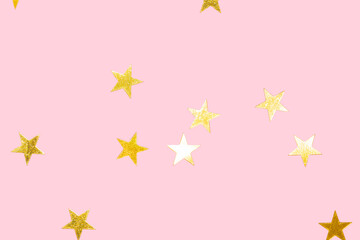 golden metallic star confetti on a pastel pink background