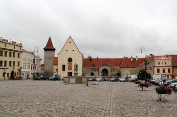 A small town of Znojmo in the Czech Republic with ancient architecture. A stone-paved square, various low-rise old houses along the square. Roofs covered with tiles. Parked cars