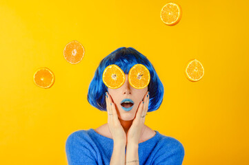 Portrait femme sur fond jaune les mains sur les joues, maquillage et perruque bleue, avec des...