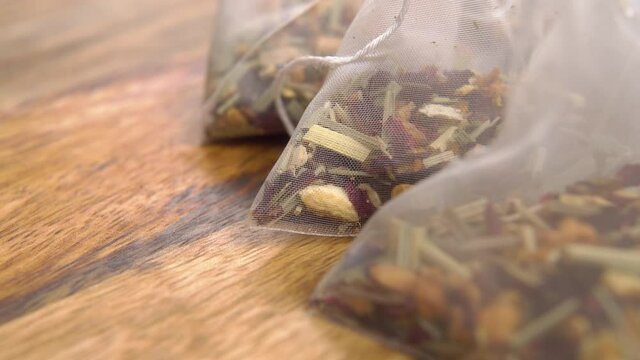 Unused mesh plastic herbal flower tea bags on texture board. Macro. Dolly shot.