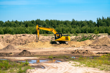An industrial yellow excavator develops in a sandpit quarry. Industry, technology, mining. Heavy industrial machinery.
