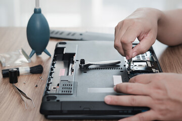 Computer literacy repair men hands use screwdriver remove nut of hard disk of laptop for check and...