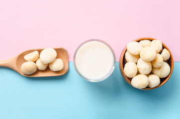 Macadamia milk in a glass and a bowl of macadamia nuts.