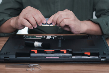 Close up hand a man hold memory (RAM) insert in RAM slot of laptop computer upgrade performance :...