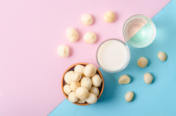 Macadamia milk in a glass and a bowl of macadamia nuts with oil.