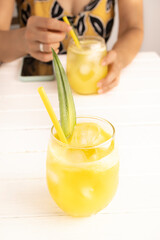 Refreshing homemade pineapple juice with ice. Girl at a table drinking a pineapple juice. Cool...