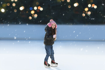 Cute little girl at outdoor ice skating rink