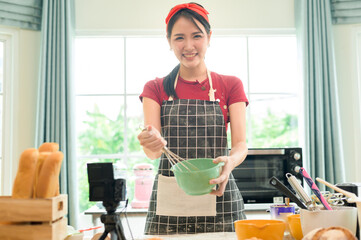 A Beautiful asian woman is making bakery ,   live streaming or recording video on social media in her house