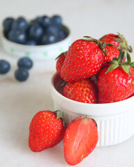 Bowl of fresh strawberries and blue berries at the background