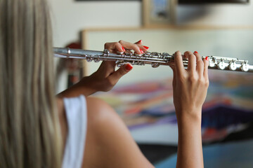 Young girl playing flute, musical instrument. Practicing the flute in the room.