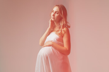 Elegant pregnant young woman standing wearing light fabric. Pregnancy, fantasy and fairy tale concept.