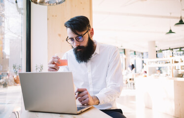 Obraz na płótnie Canvas Focused bearded man browsing laptop in cafe