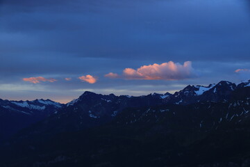 Fototapeta na wymiar Bright lit clouds over mountains near the Grimsel mountain pass.