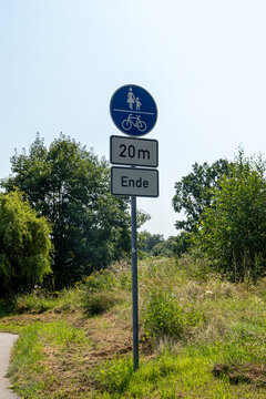 Signpost ends in 20m for pedestrians and cyclists at a wayside. Sunshine on a beautiful day. 