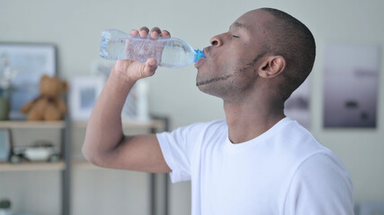 Naklejka na ściany i meble Close up of African Man Drinking Water at Home