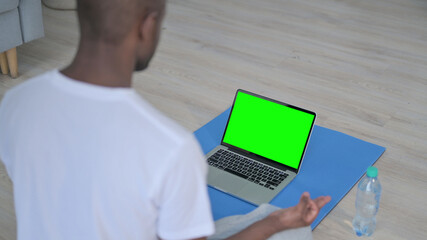 Rear View of African Man doing Yoga while Looking at Laptop with Chroma Key Screen 