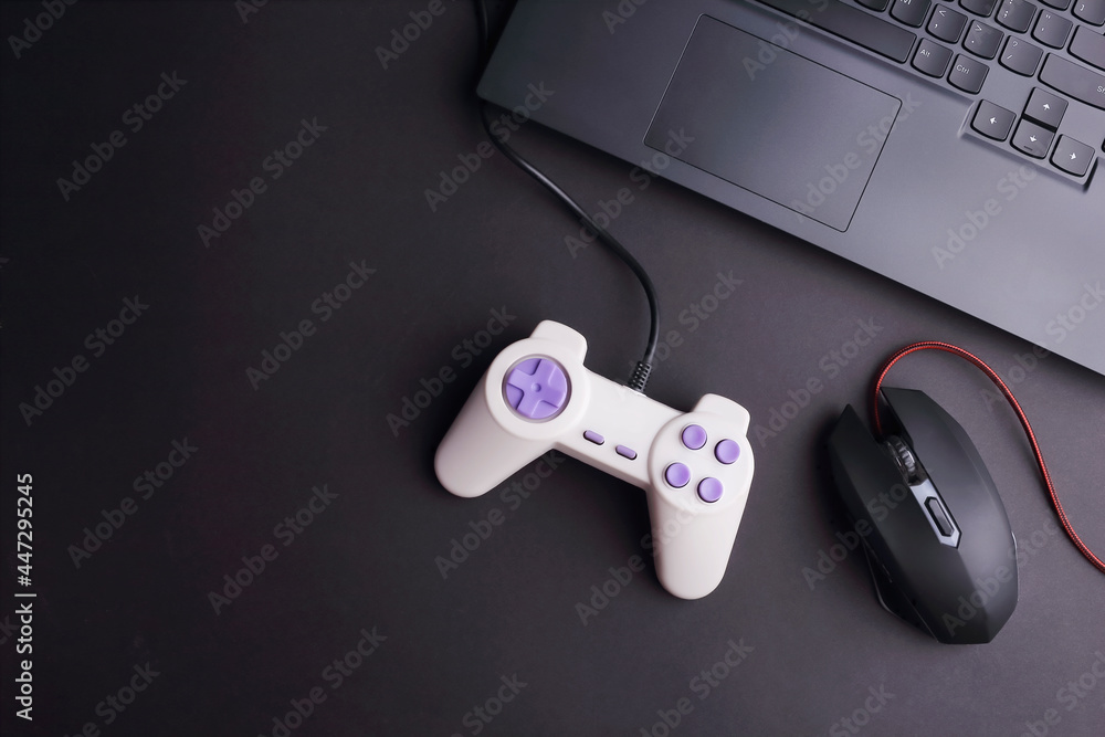 Poster joystick game controller and game mouse with laptop on black background. top view. copy space.