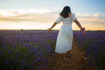 outdoors romantic portrait of young happy and attractive woman in white summer dress enjoying carefree at beautiful lavender flowers field in travel and holiday concept