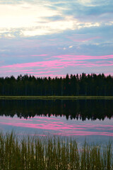 Summer night on a small pond. The sun has just set. The colors in the sky are beautiful and reflected from the surface of the water.