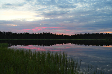 Summer night on a small pond. The sun has just set. The colors in the sky are beautiful and reflected from the surface of the water.
