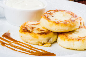 Breakfast. Cottage cheese pancake with sour cream on a white plate